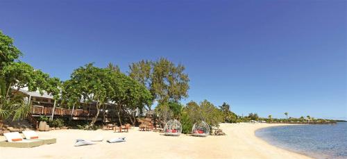 a beach with lounge chairs and trees and water at Modern Apartment in Pereybere + Pool in Pereybere