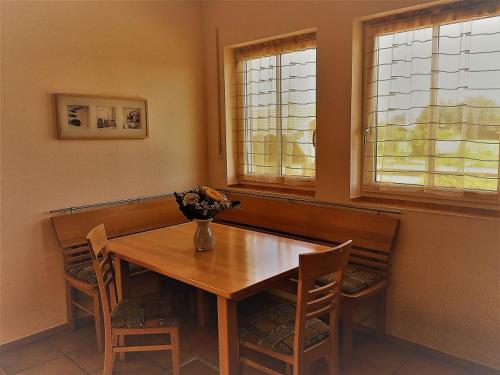 una mesa de comedor con sillas y un jarrón de flores. en Appartement Joli, en Bernau am Chiemsee