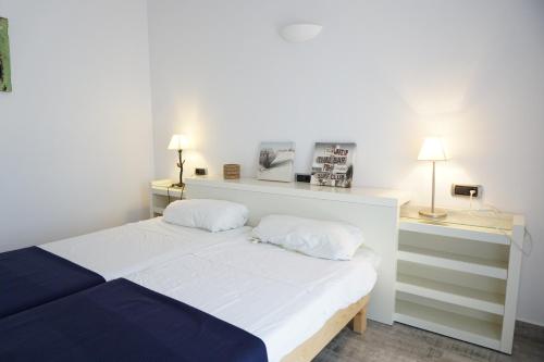 プラヤ・ミジョーンにある2 bedrooms house at Platja de Migjorn 600 m away from the beach with furnished garden and wifiのランプ2つ付きの部屋の白いベッド1台