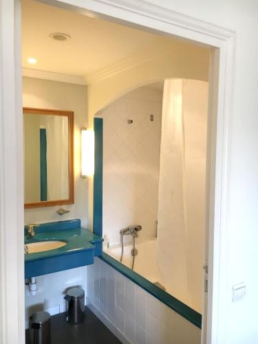 une salle de bain avec une baignoire, un lavabo et un miroir dans l'établissement Appartement cosy à Saint-André-des-Eaux de 47 m² avec jardin, à Saint-André-des-Eaux