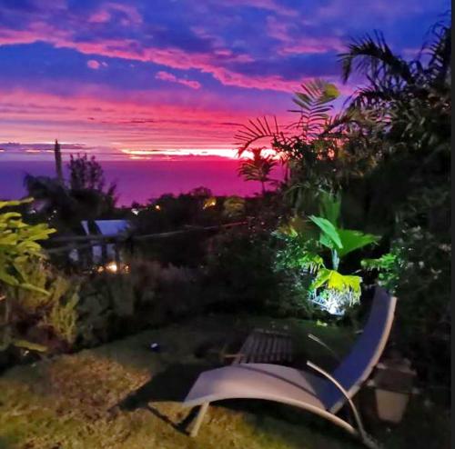 einen Sonnenuntergang über einem Garten mit einer Bank und Bäumen in der Unterkunft Appartement d'une chambre avec vue sur la mer jardin clos et wifi a Saint Leu a 5 km de la plage in Saint-Leu