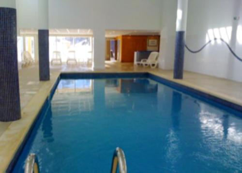 een groot zwembad met blauw water in een gebouw bij Appartement de 2 chambres avec vue sur la ville piscine partagee et terrasse a La foux d'Allos in La Foux