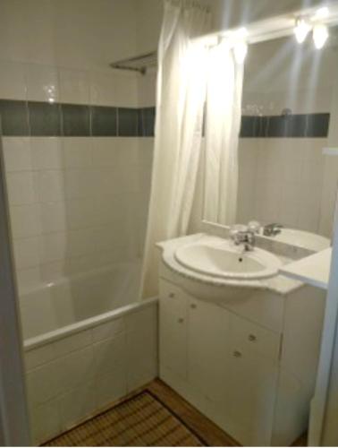 La salle de bains blanche est pourvue d'un lavabo, d'une baignoire et d'une douche. dans l'établissement Appartement convivial à La Foux d'Allos, 57 m², piscine partagée, à La Foux