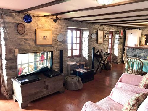 a living room with a tv and a stone wall at 2 bedrooms house with sea view terrace and wifi at Faja da Ovelha 2 km away from the beach in Fajã da Ovelha