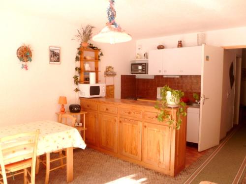 une cuisine avec des placards en bois et une table dans l'établissement Charmant appartement à Enchastrayes 38 m² avec vue montagne, à Enchastrayes