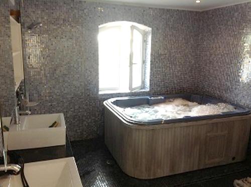 ein Bad mit einer großen Badewanne und einem Fenster in der Unterkunft Villa de 4 chambres avec piscine privee jacuzzi et jardin clos a Saint Privat des Vieux in Saint-Privat-des-Vieux