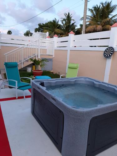 a large hot tub on a patio with chairs at Maison charmante avec vue sur la mer à Petit-Canal + Jacuzzi in Petit-Canal
