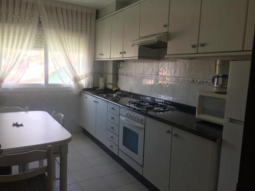 a kitchen with white cabinets and a stove and a table at 3 bedrooms appartement at Laxe 80 m away from the beach with balcony in Laxe