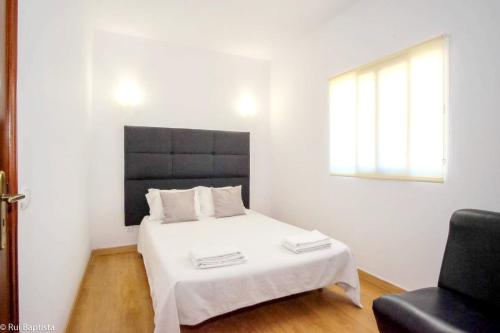 a bedroom with a white bed and a black chair at Charming House in Monchique with Shared Pool in Monchique