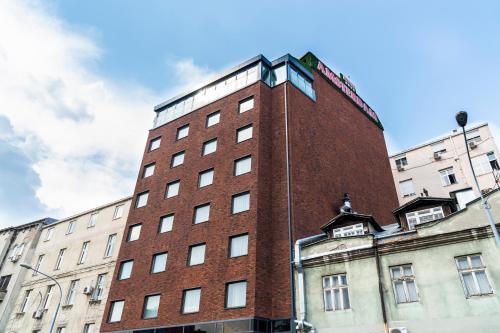 um edifício de tijolos vermelhos com um relógio em cima em Amsterdam Hotel em Belgrado