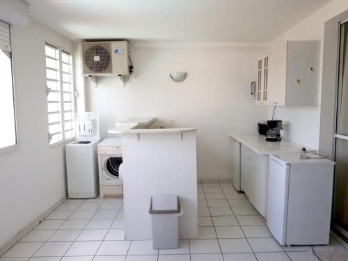 a kitchen with white appliances and a white floor at Maison d'une chambre avec vue sur la mer piscine partagee et jardin clos a Les Trois Ilets in Les Trois-Îlets