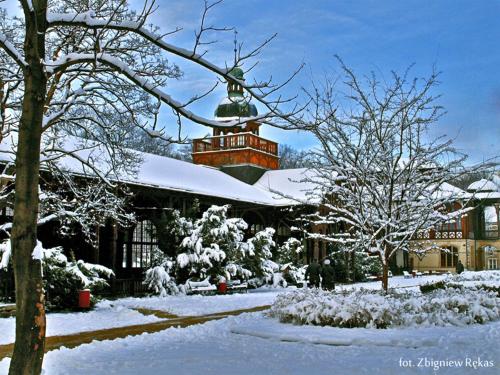 a building covered in snow with trees and bushes at Hotel Maria Helena in Szczawno-Zdrój