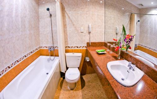 a bathroom with a tub and a toilet and a sink at Bamboo Green Riverside Hotel in Da Nang