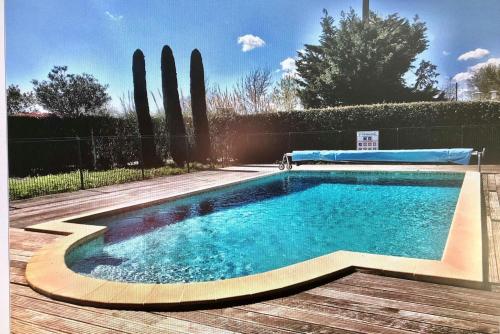 - une piscine dans une cour avec une terrasse en bois dans l'établissement Maison charmante à Cogolin + Piscine, à Cogolin