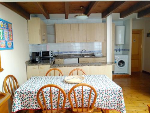 a kitchen with a table with chairs and a table and a table and chairsktop at 2 bedrooms apartement at Llanes 200 m away from the beach with wifi in Llanes