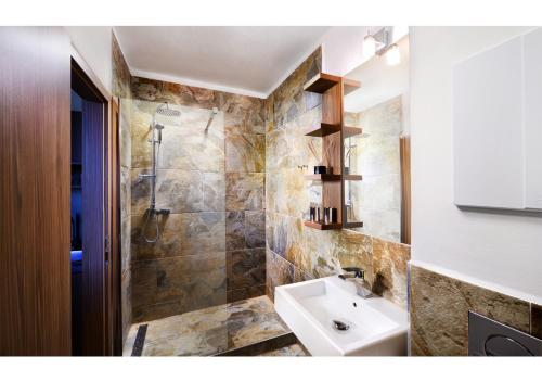 y baño con lavabo y ducha. en Apartmanový Dom TatraTravel Smokovec en Vysoké Tatry