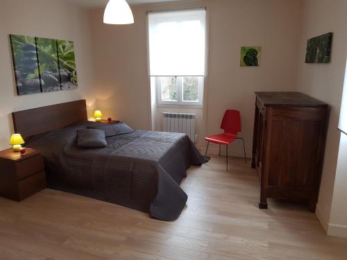 1 dormitorio con 1 cama y 1 silla roja en TRUITE FARIO, FISH AND GITES, en Lanzac