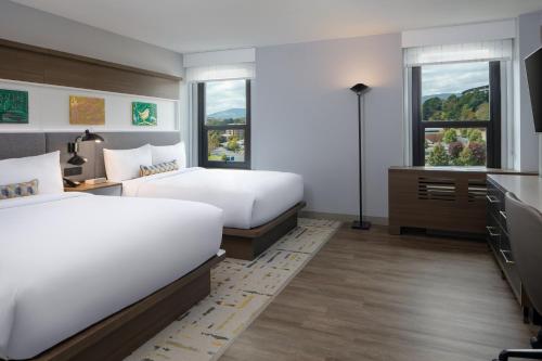 a bedroom with two beds and a desk and two windows at Hotel Indigo Chattanooga - Downtown, an IHG Hotel in Chattanooga