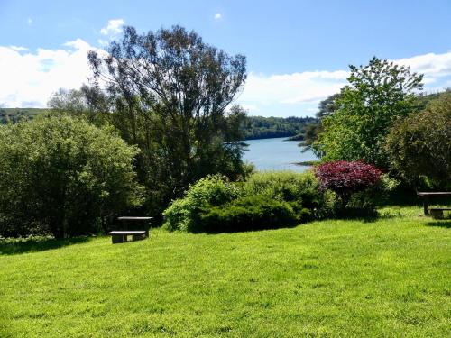 two benches in a field with a lake in the background at Lovely Sea View 2-Bed Apt in Rineen Sleeps 4 in Skibbereen