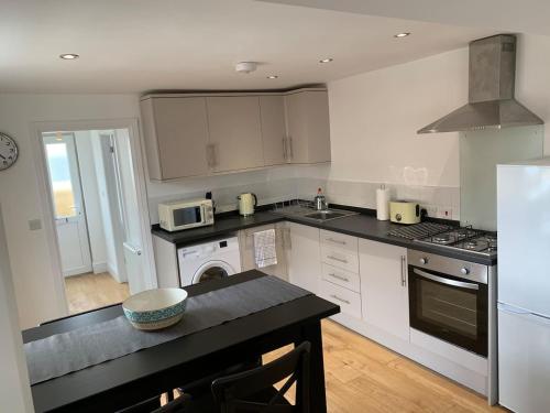 a kitchen with white cabinets and a black counter top at One Bedroom flat in Whitstable with free parking in Whitstable