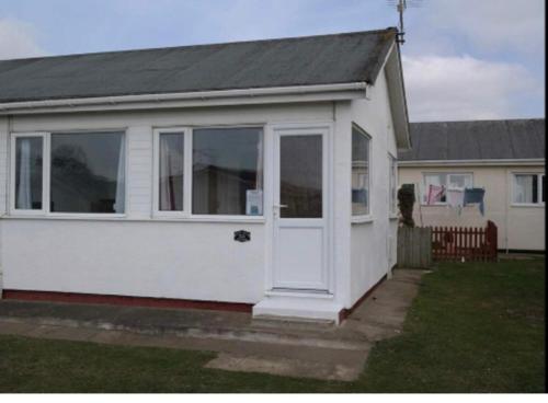 a small white house with a white door at Captivating 2-Bed chalet in Bessingby