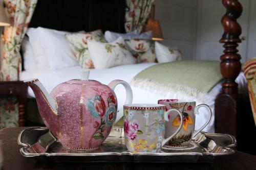 a tray with a tea pot and two cups on a bed at Spread Eagle Hotel And Spa in Midhurst