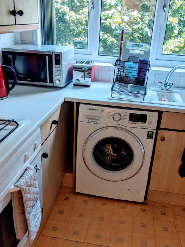 a kitchen with a washing machine and a microwave at Oaklawn Apartment - Sleeps 4 Parking & Garden in Woking