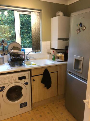 a kitchen with a washing machine and a refrigerator at Oaklawn Apartment - Sleeps 4 Parking & Garden in Woking