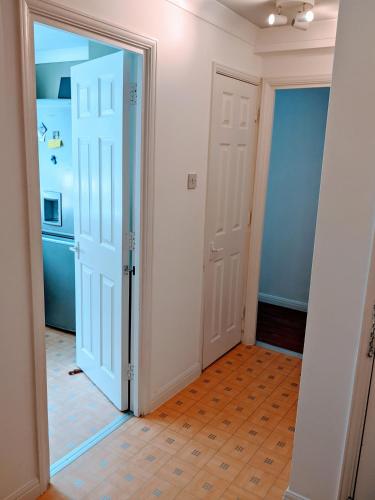 a hallway with an open door and a refrigerator at Oaklawn Apartment - Sleeps 4 Parking & Garden in Woking