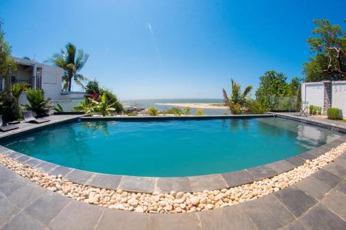 a swimming pool with a beach in the background at Villa Ilo Majunga in Mahajanga