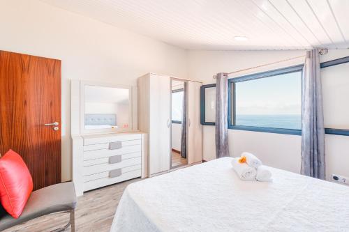 a bedroom with a bed and a chair and a window at North Coast View House in Seixal