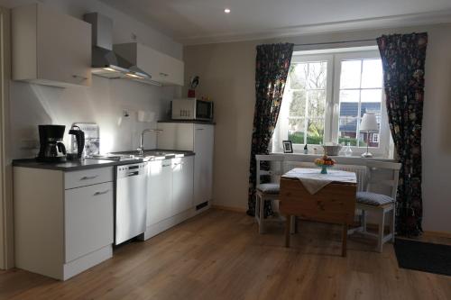 a kitchen with white cabinets and a table and a window at Apartment Erdgeschoss in Hohenlockstedt