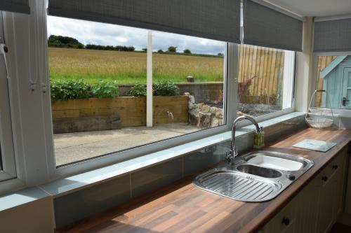 a kitchen sink and a window with a view of a field at Immaculate Inviting light and airy 2-Bed Cottage in Tibshelf