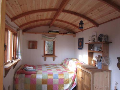1 dormitorio con cama y techo de madera en Cosy woodland off grid Shepherds Hut - Hazel en Castle Douglas