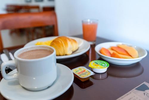 a table with a cup of coffee and plates of food at Hotel El Campin in Bogotá