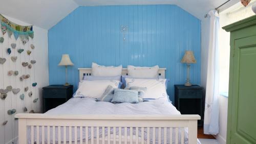 a bedroom with a white bed with blue walls at Wellspring Cottage nr Kynance Cove in Lizard