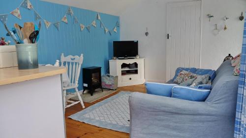 a living room with a blue couch and a tv at Wellspring Cottage nr Kynance Cove in Lizard