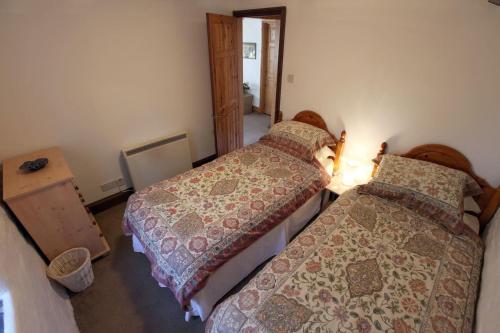 een slaapkamer met 2 bedden en een deur naar een kamer bij Inviting 2-Bed Cottage in Newcastle Emlyn in Newcastle Emlyn