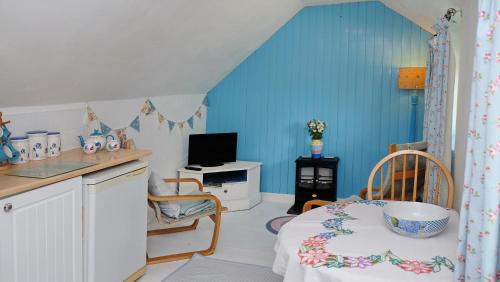 a room with a kitchen with a bed and a desk at Cosy & Quirky Cottage nr Kynance cove in Lizard