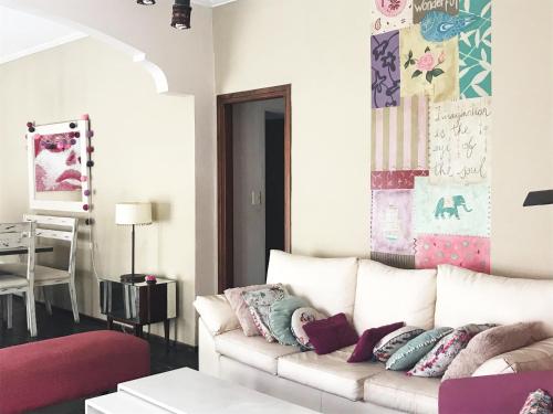 una sala de estar con un sofá blanco con almohadas en Villa Hilda - Casa con Pileta en Tandil
