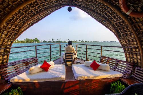 a man sitting on a boat looking out over the water at Marvel Cruise in Alleppey