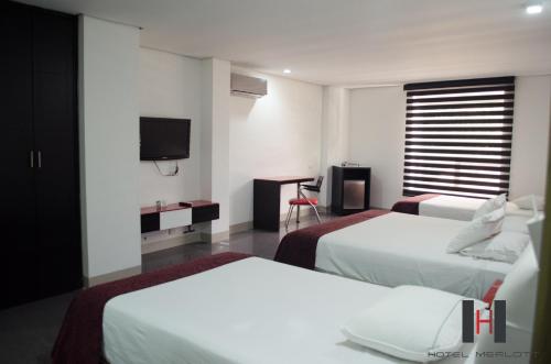 
a hotel room with two beds and a television at Hotel Merlott 70 in Medellín
