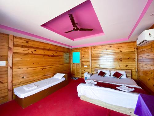 two beds in a room with wooden walls and a ceiling at Om Sai Beach Huts in Agonda