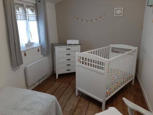 - un lit bébé blanc dans une chambre avec une commode et une fenêtre dans l'établissement Les Flots de St Val, à Saint-Valery-sur-Somme