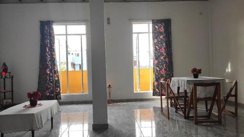 two tables and chairs in a room with two windows at Chrisber Villa in Rajagiriya