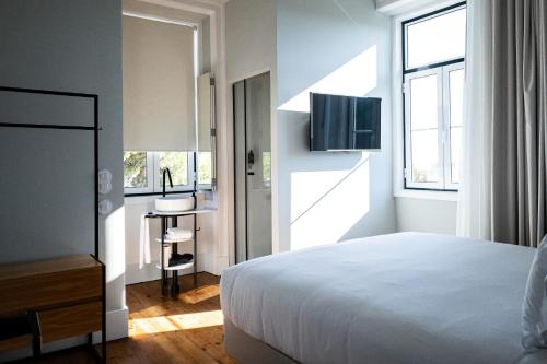 um quarto com uma cama, uma secretária e uma televisão em A House in Estoril - Adults Only em Estoril