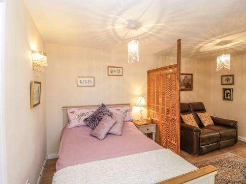 a bedroom with a bed and a leather chair at Amelyah Studio Cottage in Beautiful Countryside in Winscombe