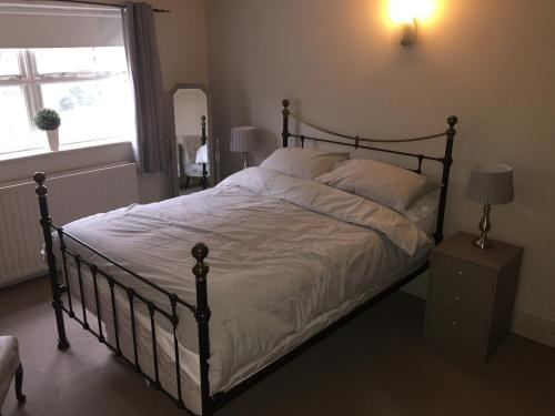 a bedroom with a large bed with white sheets and a window at Large 2-Bed House Derbyshire off Chatsworth rd in Chesterfield