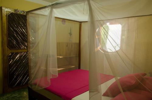 1 dormitorio con cama con dosel y suelo rosa en Hostal Corazón de Tagua en Palomino