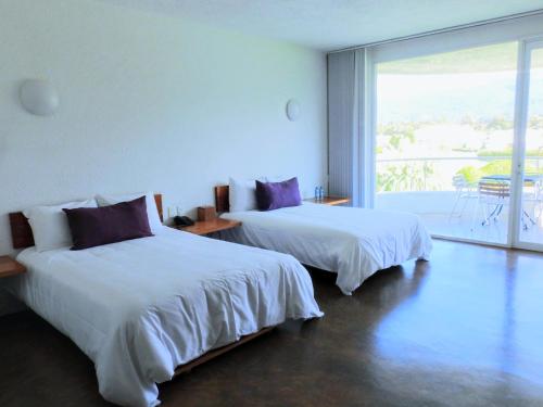 two beds in a room with a large window at Hacienda Panoaya in Amecameca de Juárez